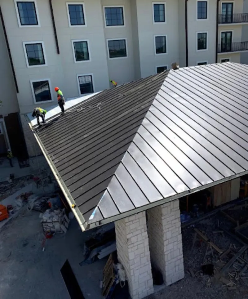 Crew installing standing seam metal roof panels on a commercial project in Sandston